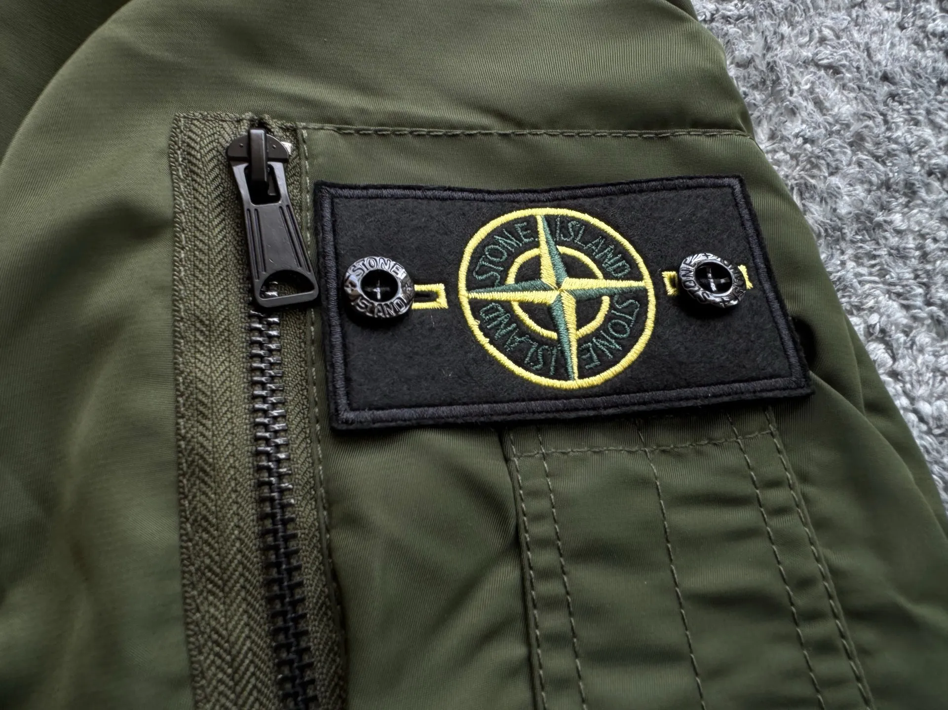 P360 Stone lsland Stone Island Medal Aviator Cotton Jacket The outer fabric is made of MA-1 flight nylon, which is a material specially used in flight and aviation. Flying nylon is a fabric specially used in flight and aviation. It is rarely used in ordinary clothing. The density of flying nylon is very high, so it is windproof and waterproof. When rain falls on the surface of the clothes, it will not penetrate immediately, but will form a small water droplet and slide off. This performance is a requirement for the development of modern jet technology. Because it is assumed that the pilot got caught in the rain before getting on the plane, he entered the cabin covered in rainwater. When flying at high altitude and at high speed, in a cabin without an environmental control system, water droplets will freeze on the pilot's body 2. Knitted baseball collar MA-1 uses a knitted collar. The collar is made of wool and can be snug around the neck and very warm. 3. Metal zippers We have very strict requirements on zippers, including smoothness and size. There was no zipper on the market that met the requirements, so we asked a zipper factory to customize a strong and durable metal zipper.  4. Double-threaded knitted cuffs The cuffs are made of double-threaded knitted fabric, narrow at the front and wide at the back. The narrow part can be tightened around the wrist to prevent wind from entering. The wide part has enough space when wearing multiple pieces under winter Color: Black Dark Army Green Size: M L.